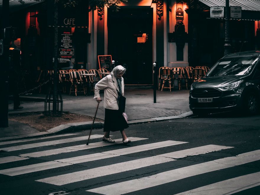 an older woman crossing a road at a crosswalk