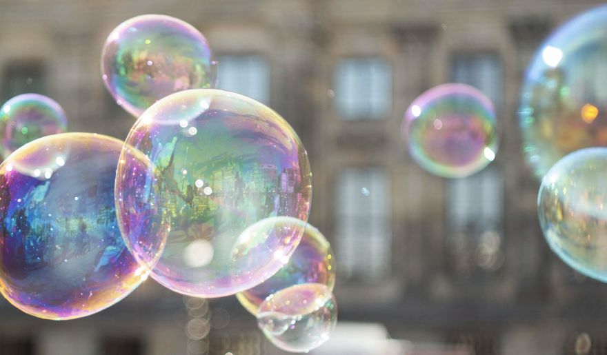 Soap bubbles floating in the air in the street, the background includes a blurred out image of an old building.