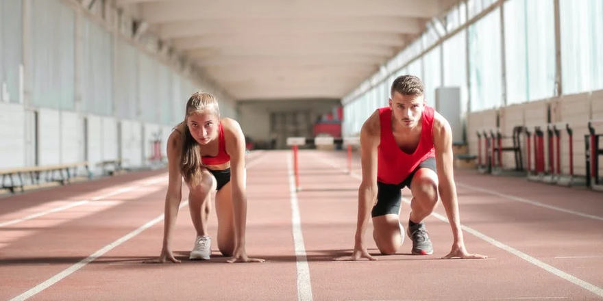 A young woman and a young man athletes prepare to run in a training hall